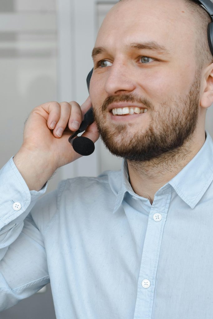 pexels-photo-7681359-7681359 Smiling man with headset providing customer service support on a call.